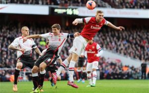 Per Mertesacker and Steven Gerrard both challenge for the ball as Martin Skrtel looks on the Gunners won the game 2-1
